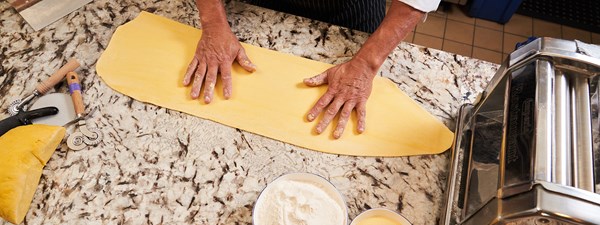 Man's hands place on pasta dough