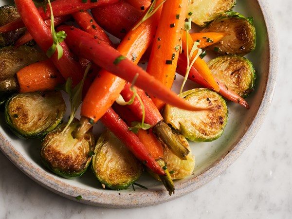 A bowl of brussels sprouts and roasted carrots.