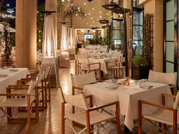 Outdoor restaurant at night with tables with white tablecloths and string lights