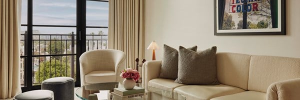 A seating area in the Library Suite. The room has a sleek  theme and features a plush cream sofa and chic fabric stools.