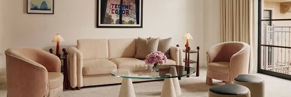 Neat living space, comfy couch, glass coffee table, adorned with an overhead portrait that reads 
