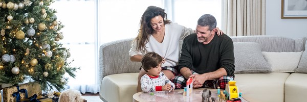 Family in a hotel suite playing with toys with a christmas tree in the background